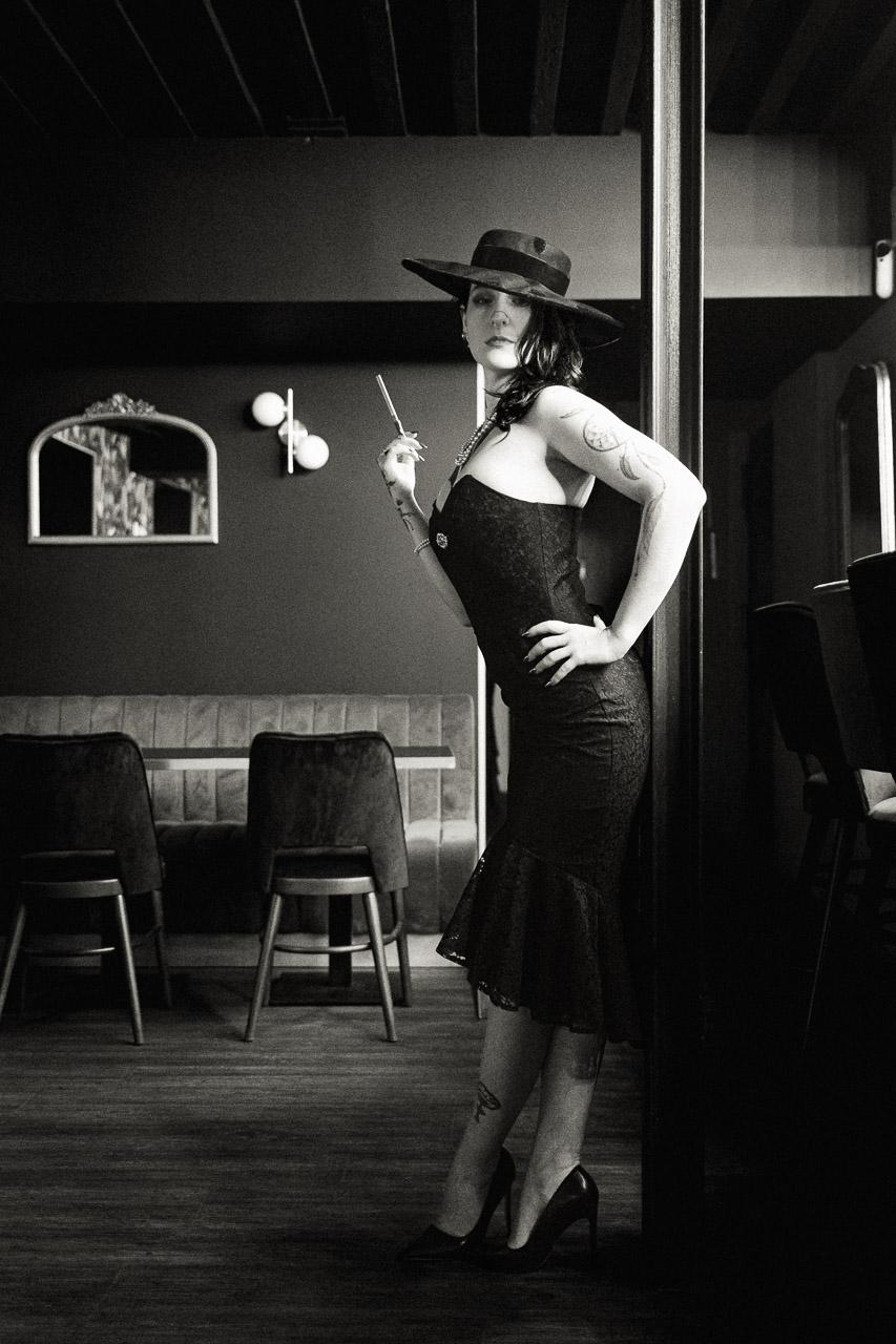 Smoke & Needles est un portrait en noir et blanc d’une femme élégante et tatouée, entre vintage et modernité, capté dans un bar au charme des années 50.