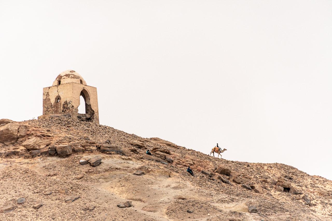 Photographie d’art de Thierry Stentzel intitulée Poussière Sainte, prise près du temple de Saqqarah en Égypte. Vue d’un chamelier descendant une pente dorée sous un ciel pâle, deux hommes assis observent la scène. Composition minimaliste, lumière douce et ambiance contemplative. Série Keshiki – photo signée, imprimée sur papier d’Art.
