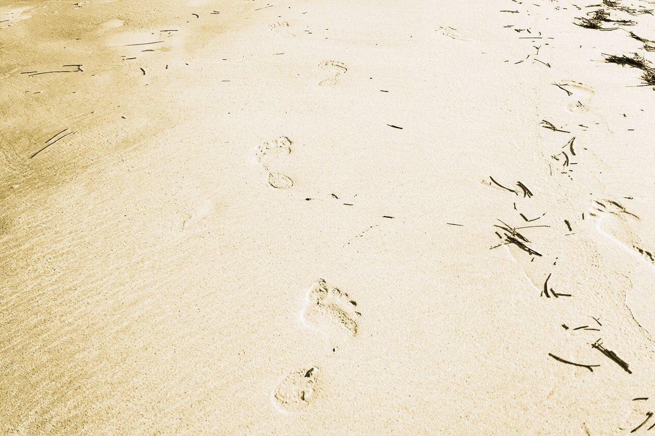 Photographie artistique de pas dans le sable intitulée Avant l’Effacement, issue de la série Mikado, évoquant le passage du temps et la trace humaine.